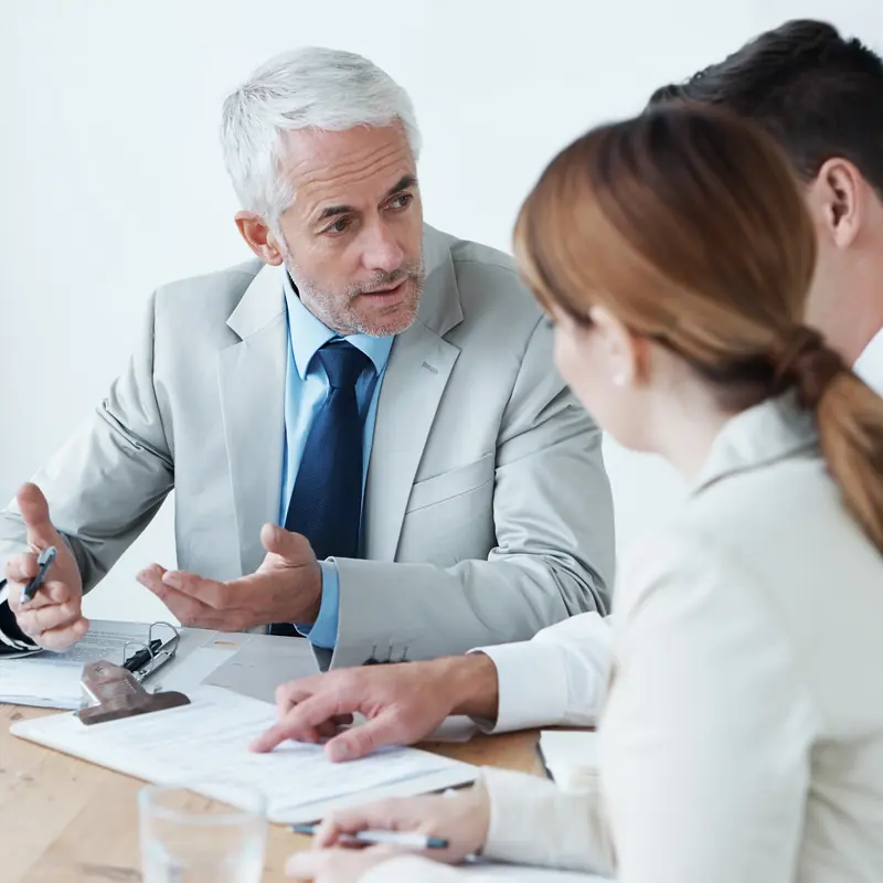 Asesor revisando documentos con dos clientes