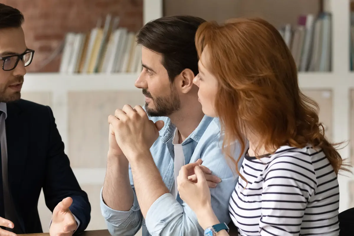 Pareja escuchando atentamente a un asesor durante una consulta